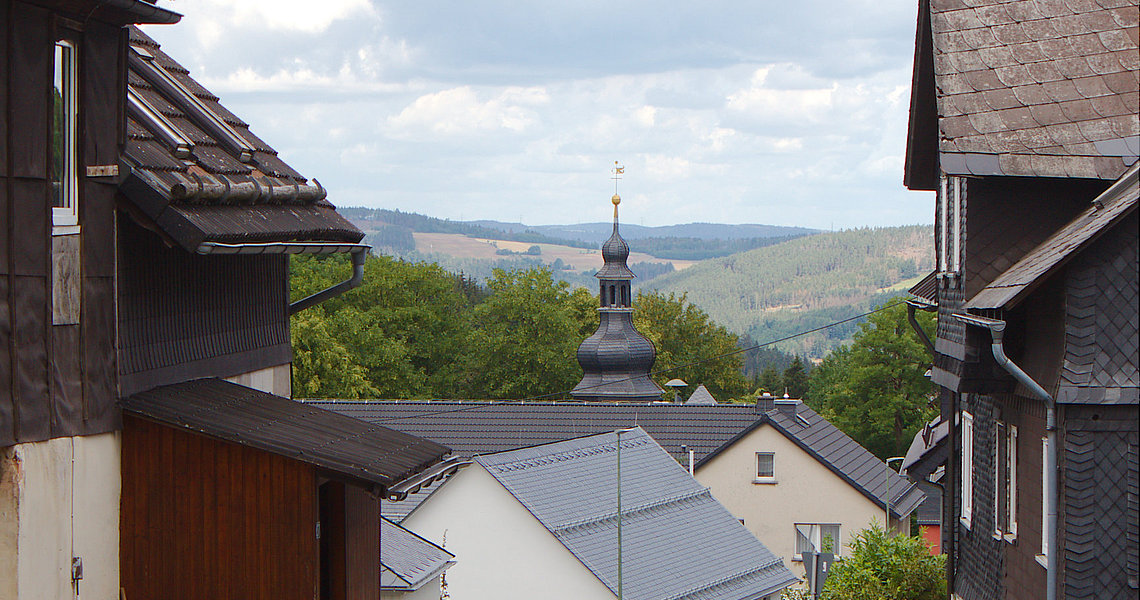 Das Foto zeigt den Blick des Fotografen entlang der Dorfstraße. Im Hintergrund ist die Kirche zu sehen. 