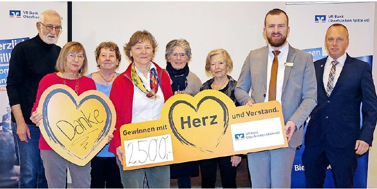 Eine Gruppe von Frauen und Männern. Alle stehen nebeneinander, halten Gutscheine in der Hand und schauen in die Kamera.