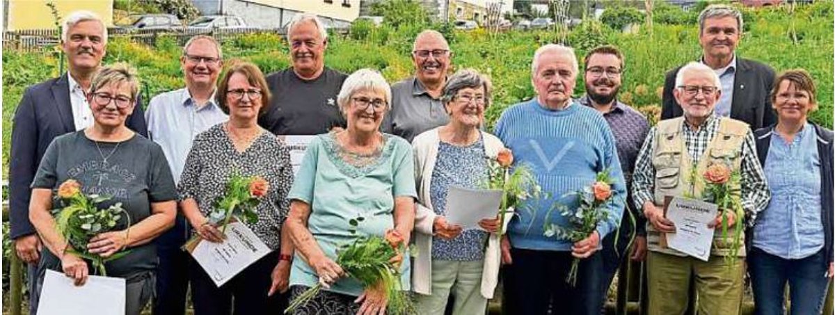 Im Vordergrund sind von links nach rechts die Geehrten der Gesangvereine zu sehen. Vier Frauen und zwei Männer mit den verliehenen Urkunden und je einer Rose. Dahinter stehen noch Bürgermeister, Chorleiter und Vorstände.