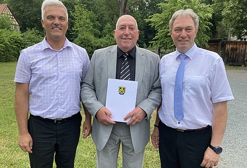 Das Foto zeigt Bürgermeister Timo Ehrhardt und Landrat Klaus Löffer. Zwischen den beiden steht Johannes Haase und hält seine Auszeichnung in den Händen. Alle drei lächeln in die Kamera. 