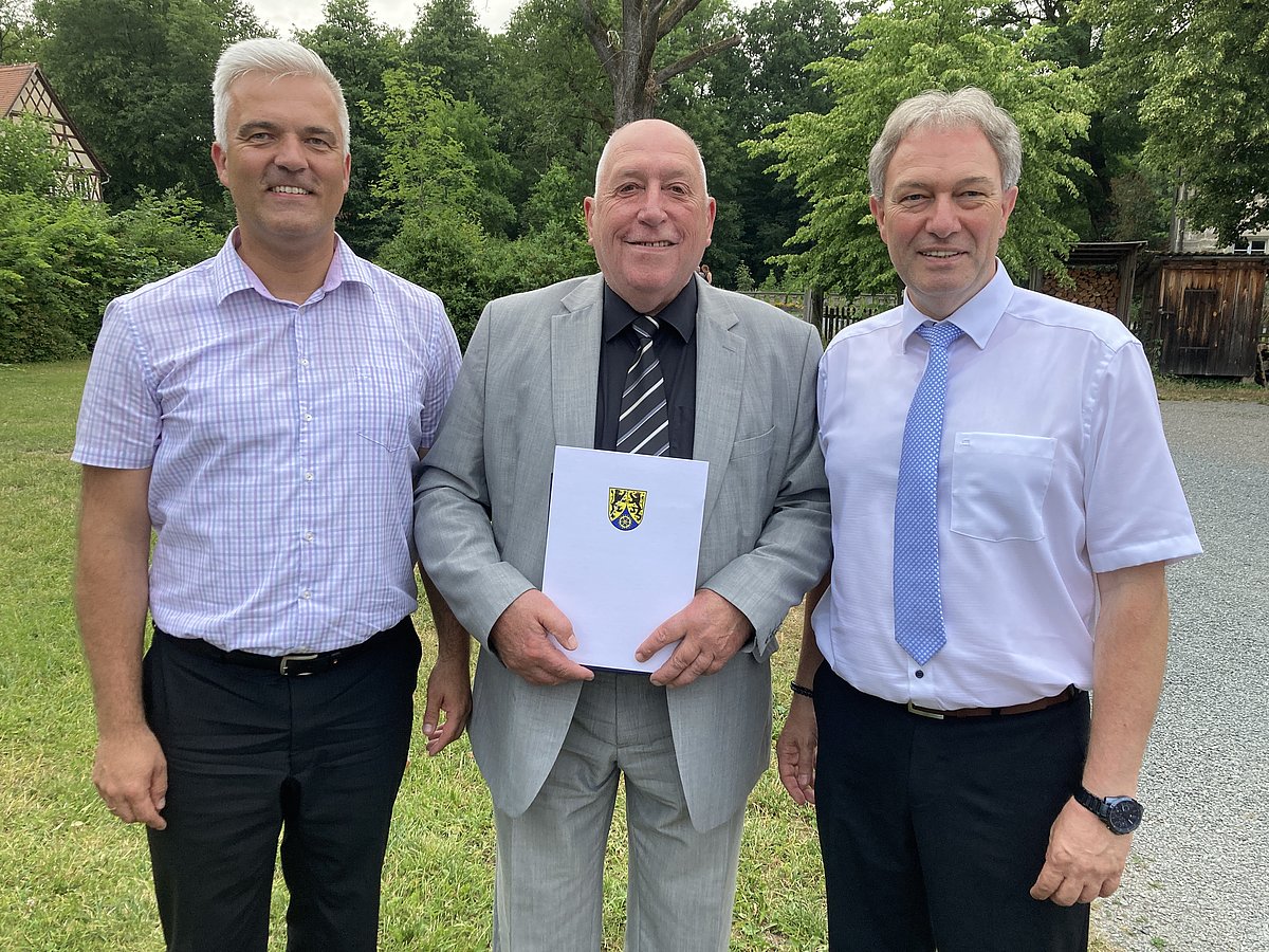 Das Foto zeigt Bürgermeister Timo Ehrhardt und Landrat Klaus Löffer. Zwischen den beiden steht Johannes Haase und hält seine Auszeichnung in den Händen. Alle drei lächeln in die Kamera.