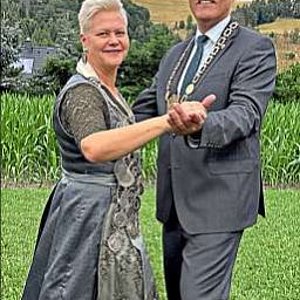 Schützenkönigin Katja und Bürgermeister Timo Ehrhardt tanzen im grünen Gras. Sie trägt ein elegantes graues Dirndl und ihre Königskette, er im grauen Anzug mit Amtskette. Im Hintergrund ist der Sommerberg Richtung Steinbach/Haide zu sehen.
