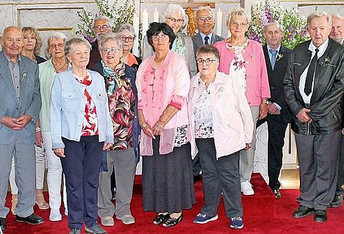 Eine Gruppe von älteren Menschen. Sie stehen in einer Kirche und schauen alle in die Kamera.