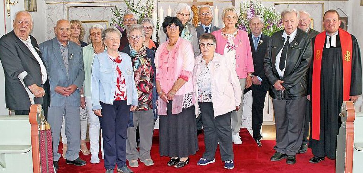 Eine Gruppe von älteren Menschen. Sie stehen in einer Kirche und schauen alle in die Kamera.