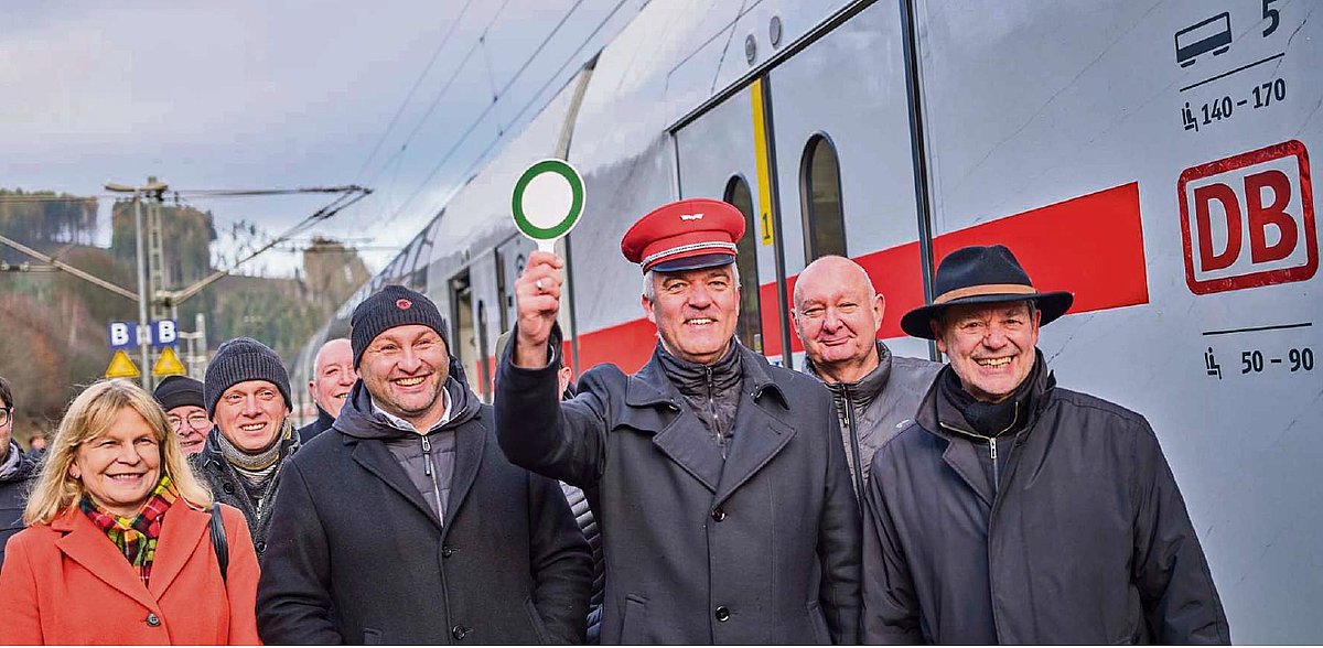 Eine Gruppe von Menschen, darunter der Bürgermeister Timo Ehrhardt, stehen am Bahngleis neben dem IC.