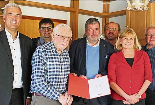 Das Foto zeigt eine Gruppe von Menschen, in deren Mitte der Jubilar steht. Sie alle schauen in die Kamera.