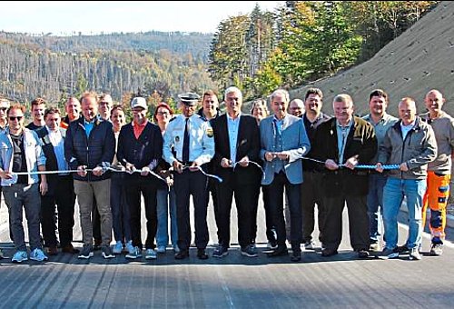 Eine große Gruppe an Menschen stehen auf einer Straße und halten ein weißes Sperrband in den Händen. 