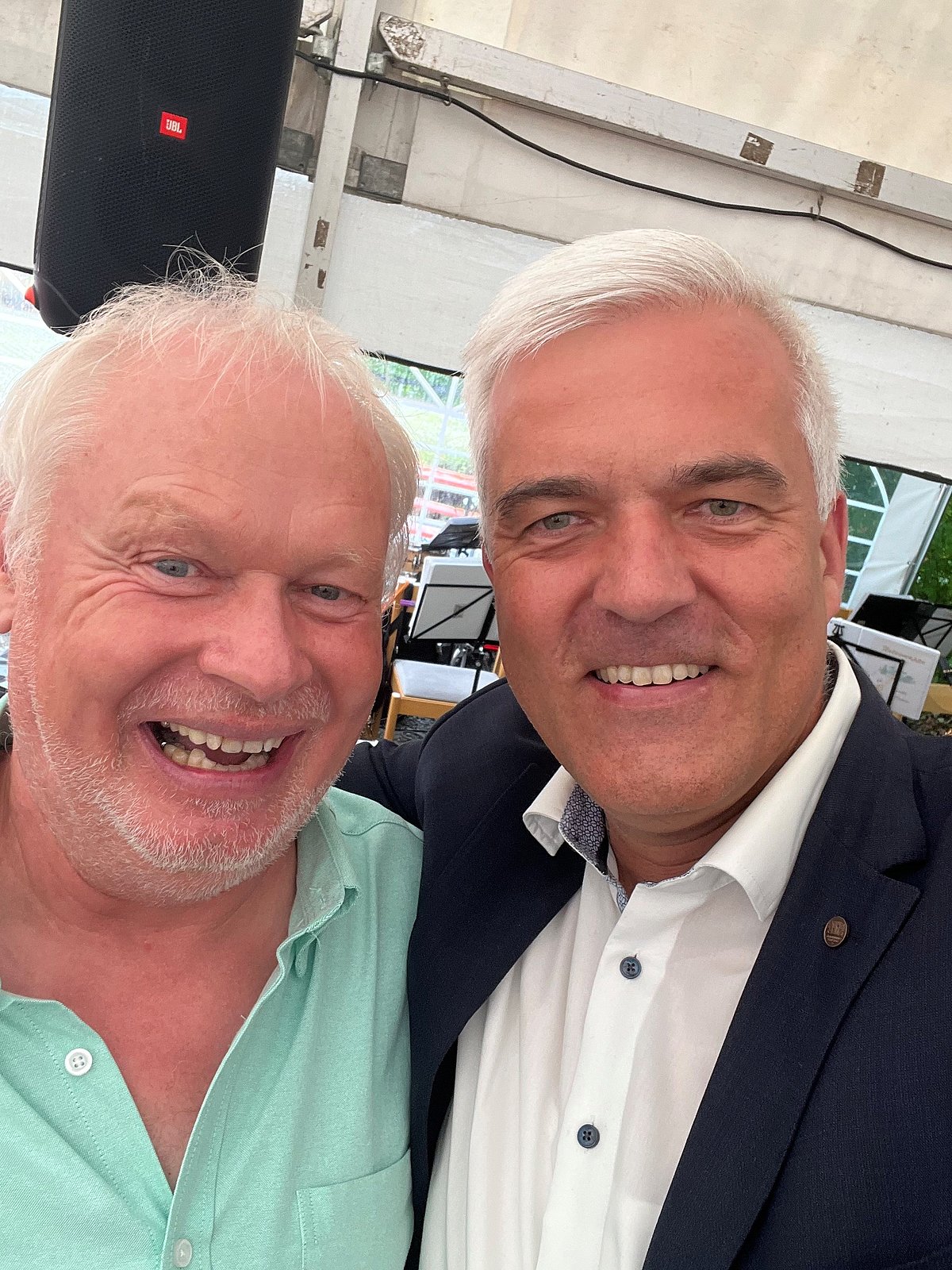 Selfie von zwei Männern. Beide haben graue Haare und lachen in die Kamera.