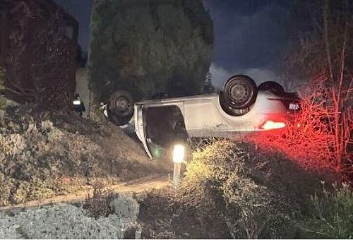 Ein Auto liegt auf seinem Dach in einem Garten. Die Bremslichter leuchten rot.l