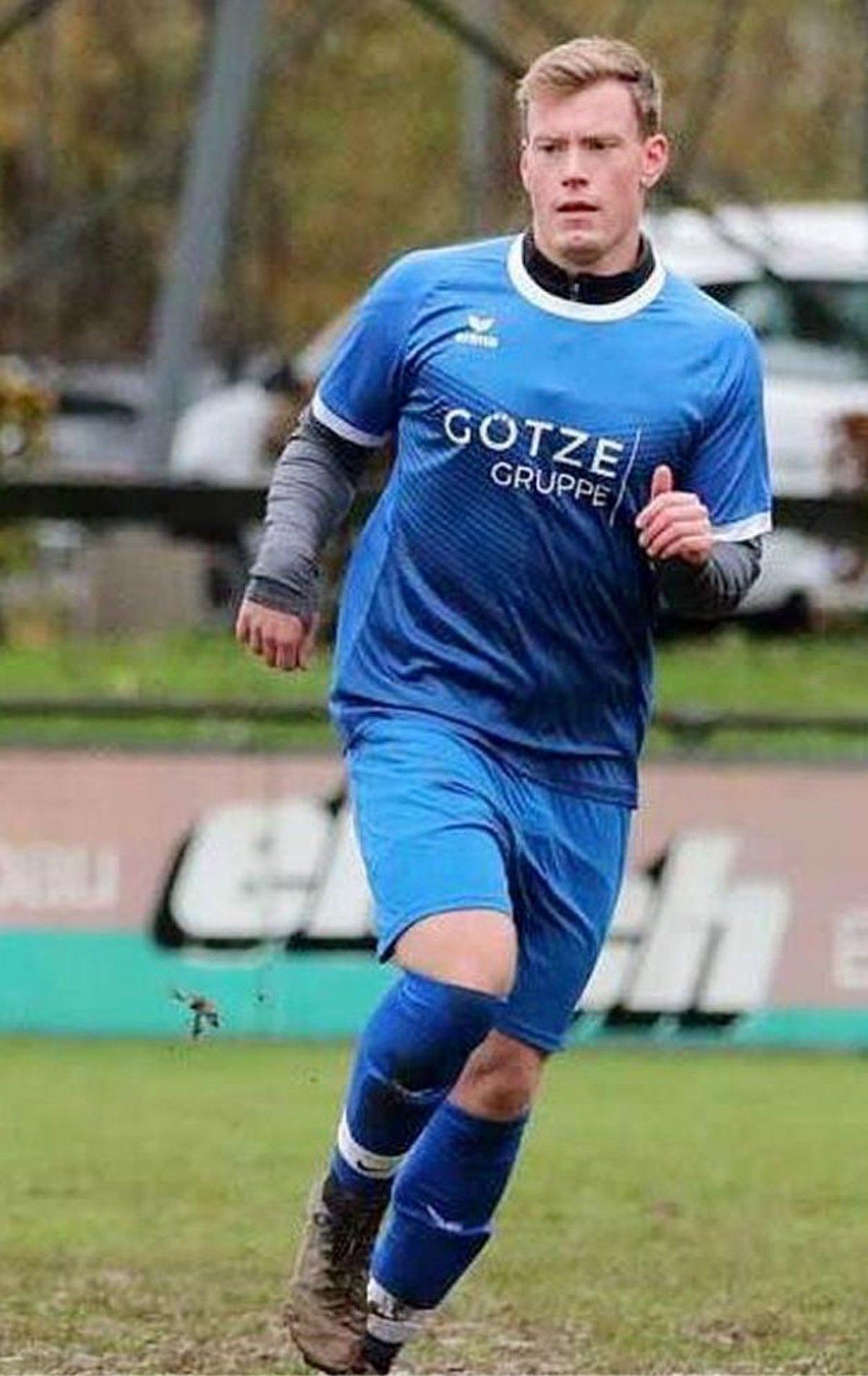 Zu sehen ist ein junger Fußballer des TSV Ludwigsstadt mit blauem Trikot in Aktion auf schlechtem Geläuf.