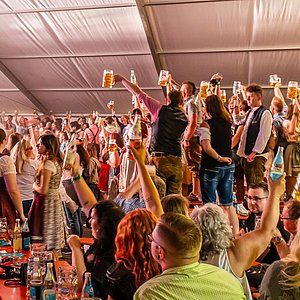 Viele feiernde Menschen in einem Festzelt.