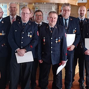 Eine Gruppe von Männern in Feuerwehruniform. Einige halten eine Urkunde in der Hand.