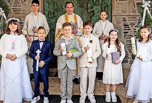 Die Kinder stehen in einer Gruppe mit Ihren Kommunionskerzen
