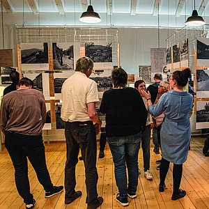 Das Foto zeigt mehrere Menschen, die sich die Fotos der Sonderausstellung ansehen und scheinbar miteinander im Gespräch sind. 