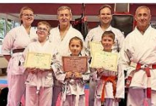 Auf dem Foto sind vier Erwachsene und drei Kinder mit Urkunden zu sehen.