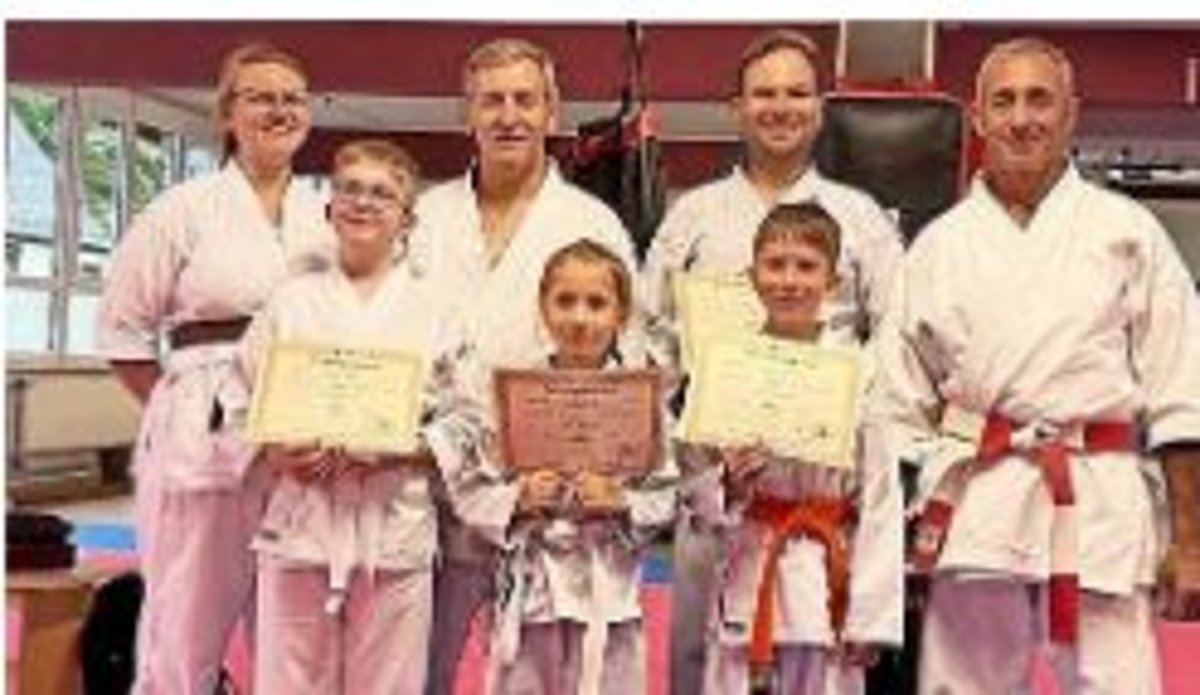 Auf dem Foto sind vier Erwachsene und drei Kinder mit Urkunden zu sehen.