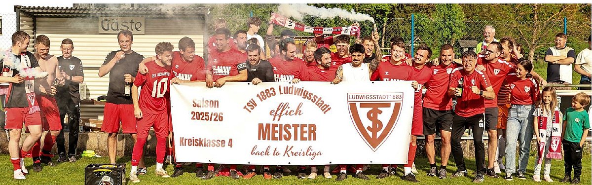 Eine feierende Fußballmannschaftr in roten Trikots. Sie stehen in mehreren Reihen hintereinander. Vorn halten sie ein großes Banner mit ihrem Namen und Logo.
