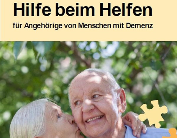 Ein Flyer. Darauf ein Bild von einer älteren Frau mit grauen Haaren und einem älteren Mann mit wenig Haaren. Sie küsst ihn auf die Wange. Er lächelt.