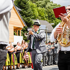 Das Bild zeigt die Musikanten während des Festumzuges. Zentral ist ein Trompeter zu sehen, der auch Schütze ist und daher in seiner Schützenuniform im Zug mitläuft.