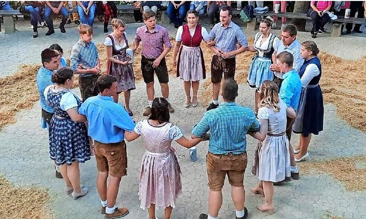 Das Foto zeigt den Tanzanger mit der Kirchweihgesellschaft. Die Damen tragen Dirndl, die Männer Lederhosen. Sie stehen in einem großen Kreis.