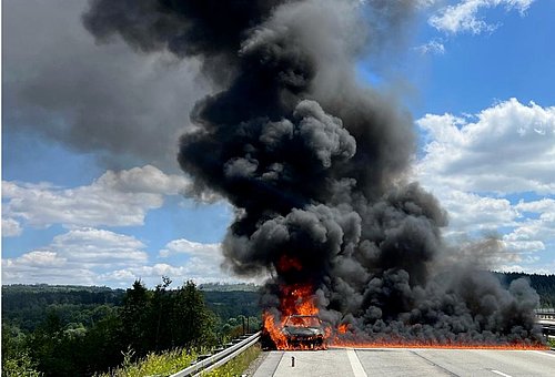 Auf dem Bild ist das brennende Pannenfahrzeug und eine dicke schwarze Rauchwolke zu sehen.