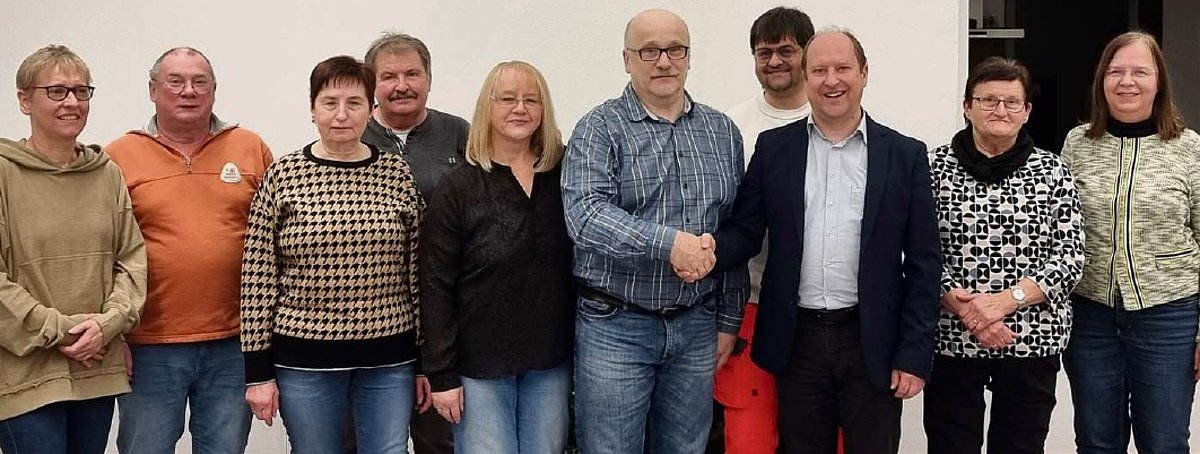 Eine Gruppe von Menschen, die nebeneinander stehen und in die Kamera schauen.
