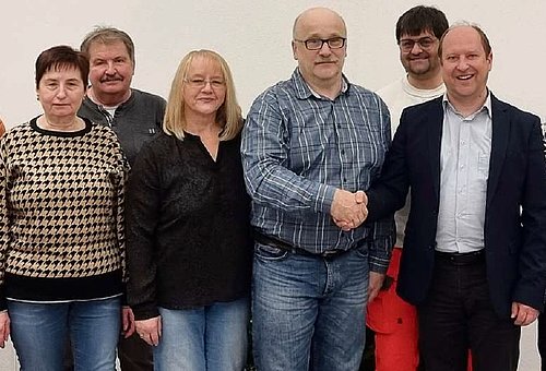 Eine Gruppe von Menschen, die nebeneinander stehen und in die Kamera schauen. 