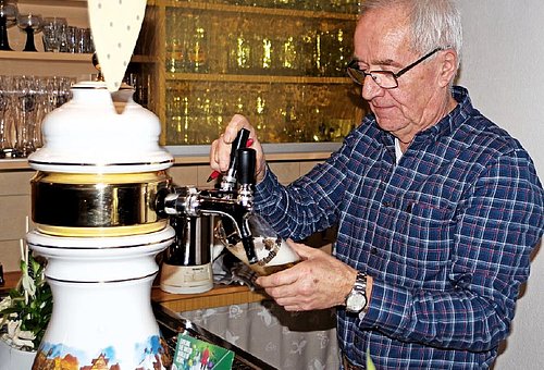 Ein Mann steht hinter einer Gastotheke und zapft ein Bier. 