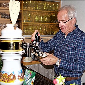 Ein Mann steht hinter einer Gastotheke und zapft ein Bier.