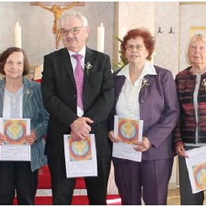 Vor einem Kirchenaltar stehen vier Frauen und zwei Männer. Einer der beiden trägt die schwarze Robe eines Pfarrers.