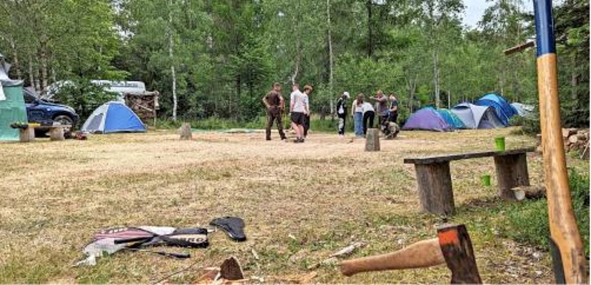 Das Foto zeigt einen Zeltplatz mit einer Gruppe von Jugendlichen im Hintergrund.