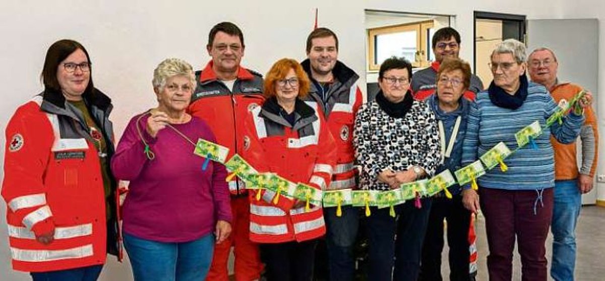 Das Bild zeigt Frauen und Männer mit einer Kette aus Geld als Spendenübergabe