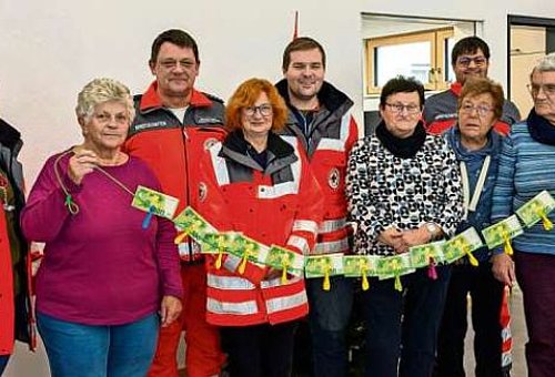 Das Bild zeigt Frauen und Männer mit einer Kette aus Geld als Spendenübergabe