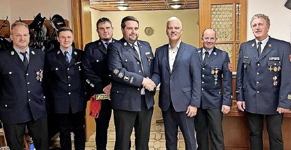 Die Mitglieder der Feuerwehr stehen in Uniform in einer Reihe. Es sind alles Männer. Vorn reicht Bürgermeister Timo Ehrhardt einem uniformierten Mann die Hand zur Gratulation.