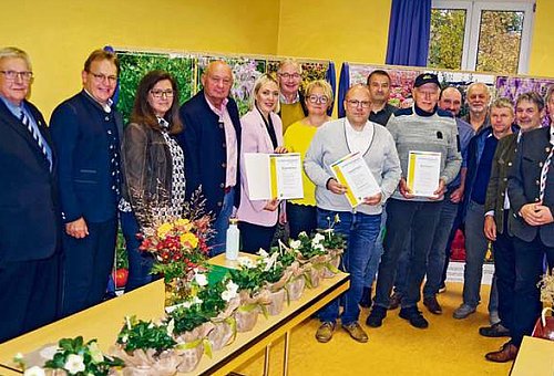 Das Foto zeigt eine große Gruppe an Menschen. Einige halten Urkunden in der Hand. Alle schauen in die Kamera.