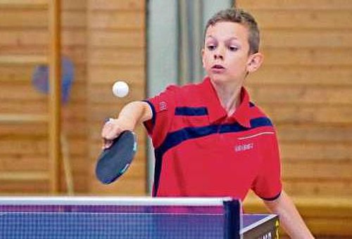 Ein Junge mit Schläger und Ball beim Tischtennisspielen