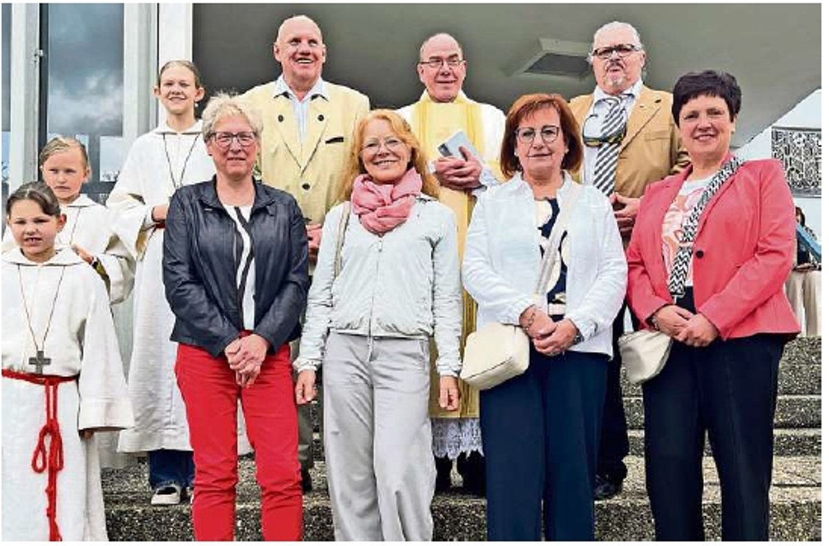Eine Gruppe von Menschen, darunter drei Kinder in weißer Kleidung und 7 erwachsene Menschen. Sie alle lächeln in die Kamera.