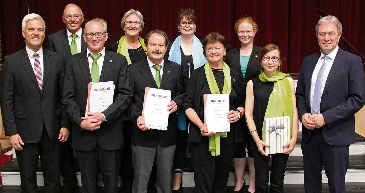 Das Foto zeigt die Geehrten, ganz außen den Landrat Klaus Löffler und auf der anderen Seite Bürgermeister Timo Ehrhardt. Alle lächeln in die Kamera. 