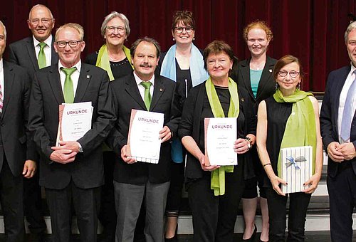 Das Foto zeigt die Geehrten, ganz außen den Landrat Klaus Löffler und auf der anderen Seite Bürgermeister Timo Ehrhardt. Alle lächeln in die Kamera.