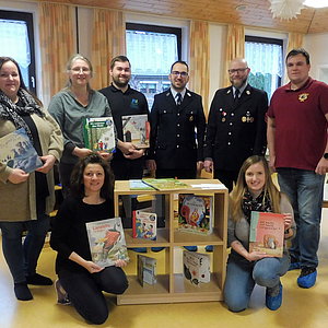 Eine Gruppe aus 4 Frauen und vier Männern, darunter drei Männer in Feuerwehruniform. Sie alle schauen in die Kamera und lächeln.