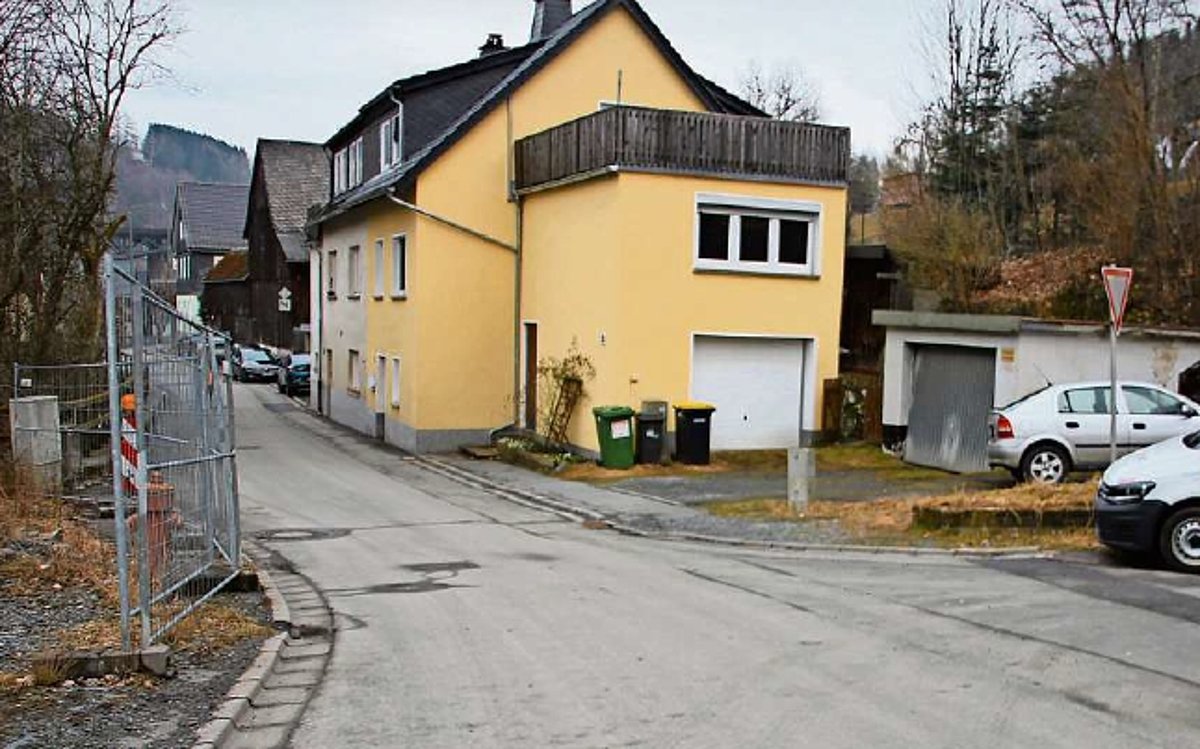 Eine sehr enge Straße auf deren einer Seite ein gelben Wohnhaus steht. Die andere Straßenseite ist mit Bauzäunen zugestellt.