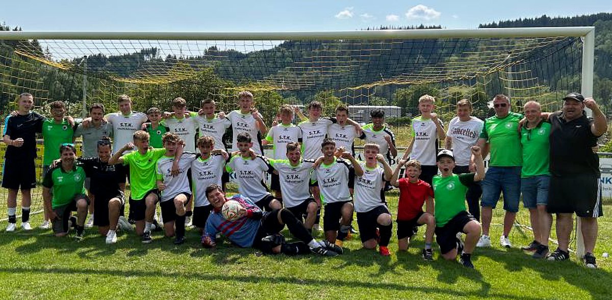Das Foto zeigt die Mannschaft mit Spielern, Trainern und Betreuern. Die Fussballspieler jubeln in die Kamera. 