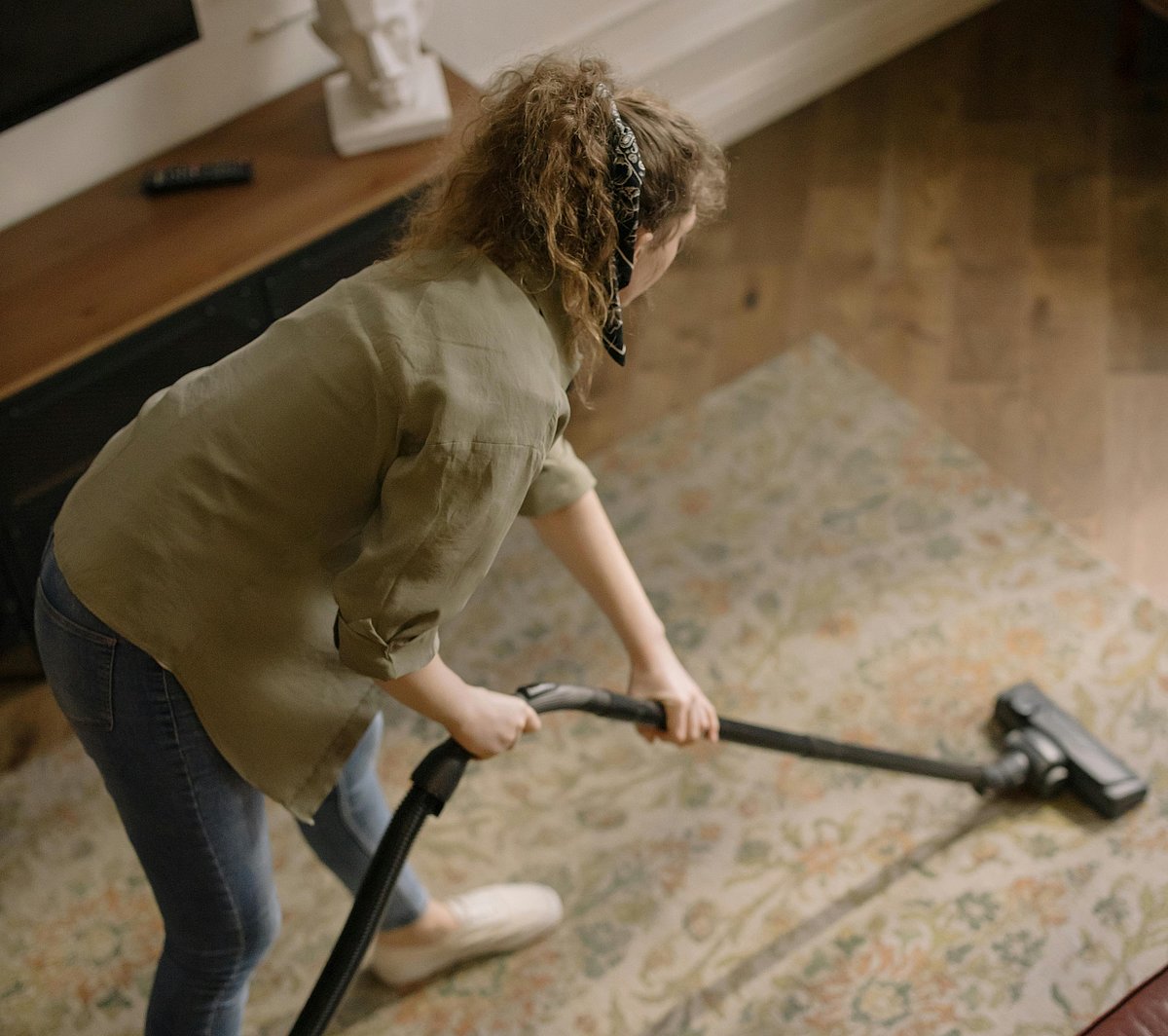 Eine Frau saugt mit einem Staubsauger einen Teppich