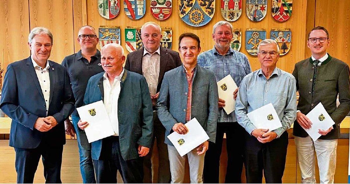 Eine Gruppe von Männern schauen in die Kamera. Sie halten Urkunden in der Hand. Am linken Bildrand steht Landrat Klaus Löffler. 