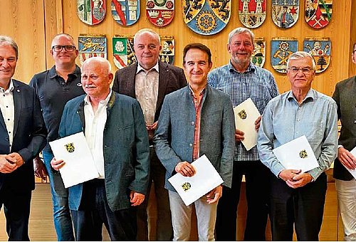 Eine Gruppe von Männern schauen in die Kamera. Sie halten Urkunden in der Hand. Am linken Bildrand steht Landrat Klaus Löffler. 