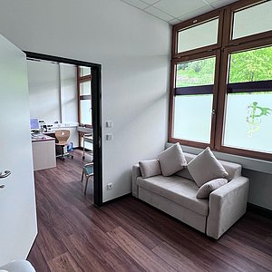 Das Foto zeigt den Wartebereich und eine geöffnete Tür zeigt in ein Behandlungszimmer