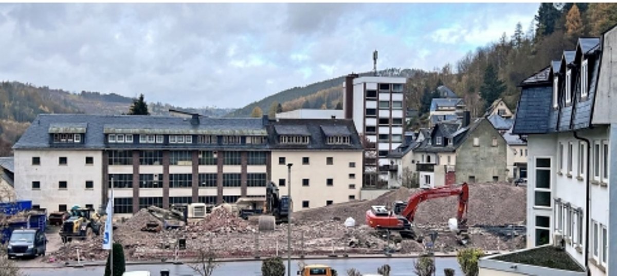 Das Foto zeigt die Baustelle, auf der das Gebäude der Sparkasse abgerissen wird. Zu sehen sind große Bauschuttberge und ein Bagger.