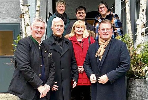 Eine Gruppe von Menschen stehen auf einer Außentreppe und lächeln in die Kamera.