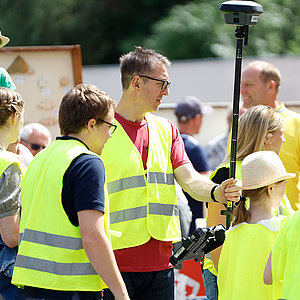 Kinder und Erwachsene in gelben Warnwesten gehen auf Schnitzeljagd.