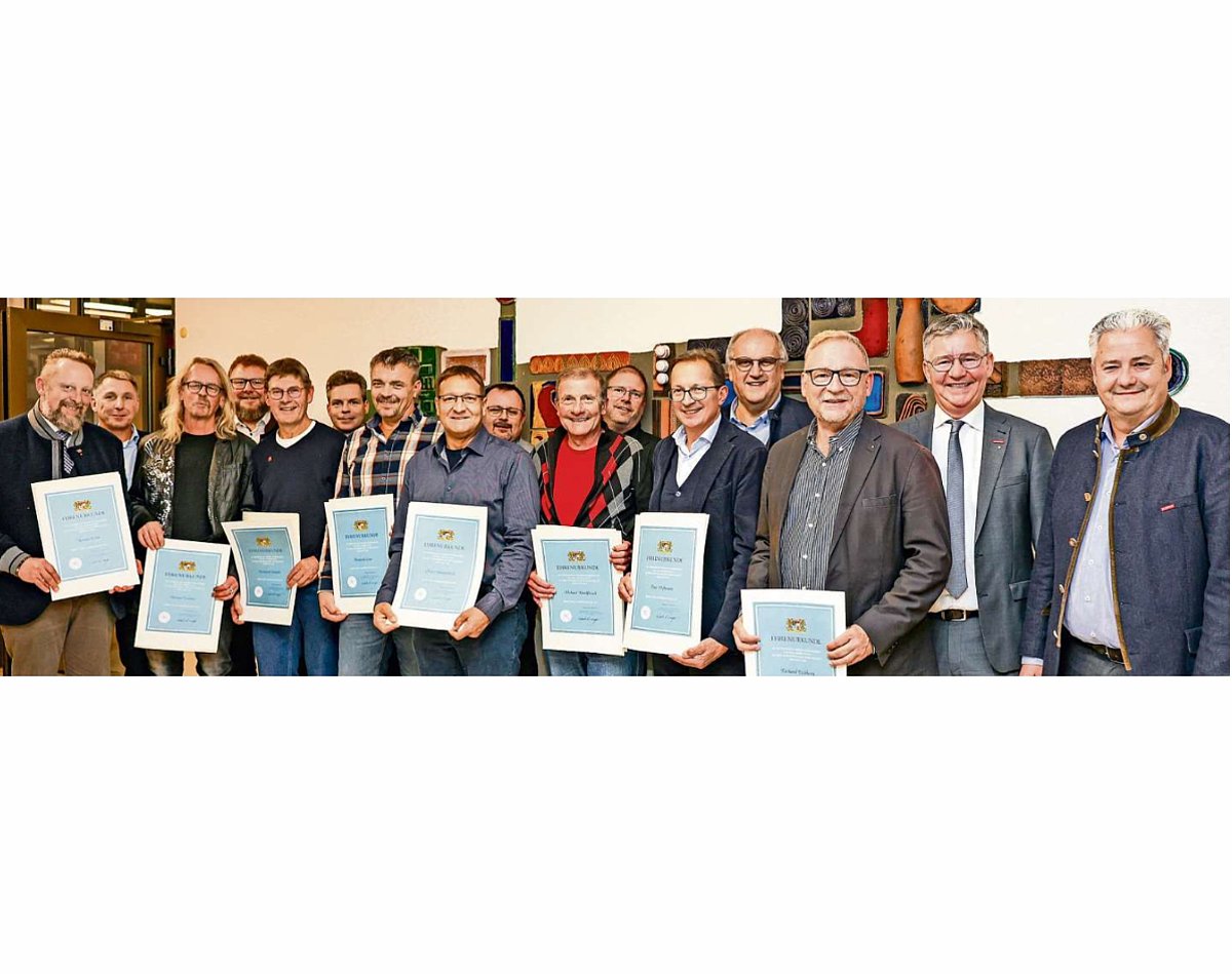 Eine Gruppe von Menschen. Alle außer zwei Männern halten eine Urkunde in den Händen. Alle lächeln in die Kamera.